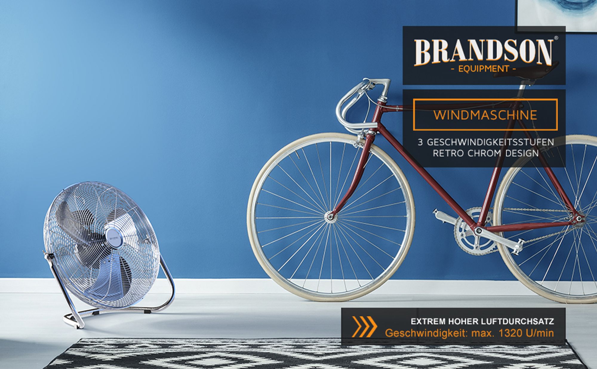Windmaschine im Retro-Design vor blauer Wand neben Fahrrad mit Rennlenker