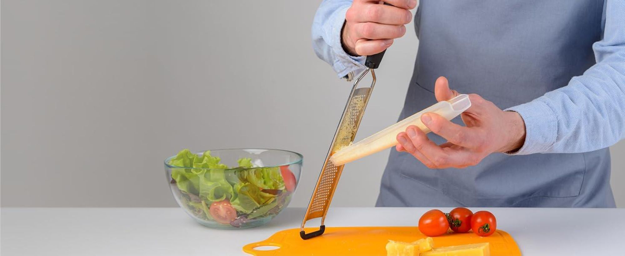 Heben Sie den Behälter am oberen Rand an und führen Sie den Schaber über die Reibefläche.