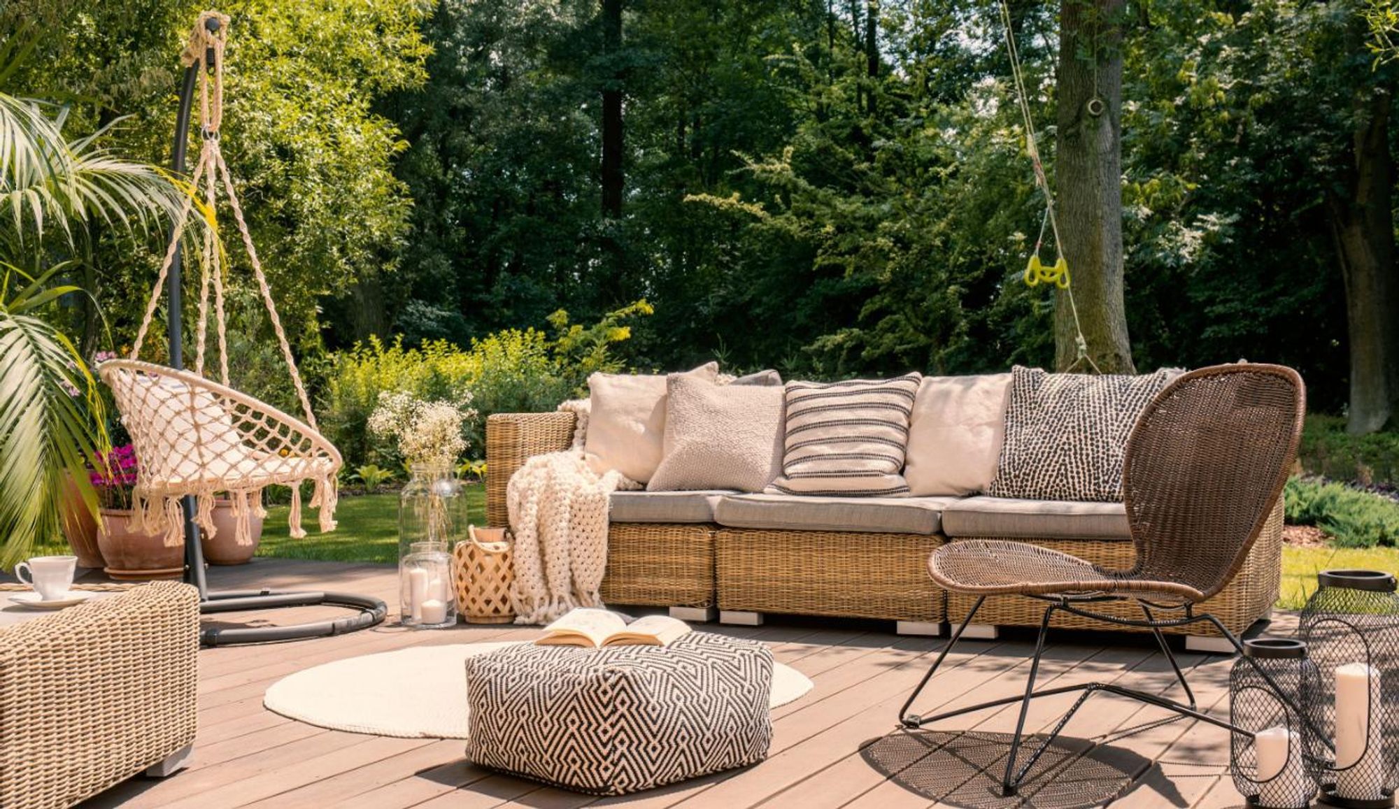 Terrasse mit Gartenlounge und Hängesessel, Bäume im Hintergrund
