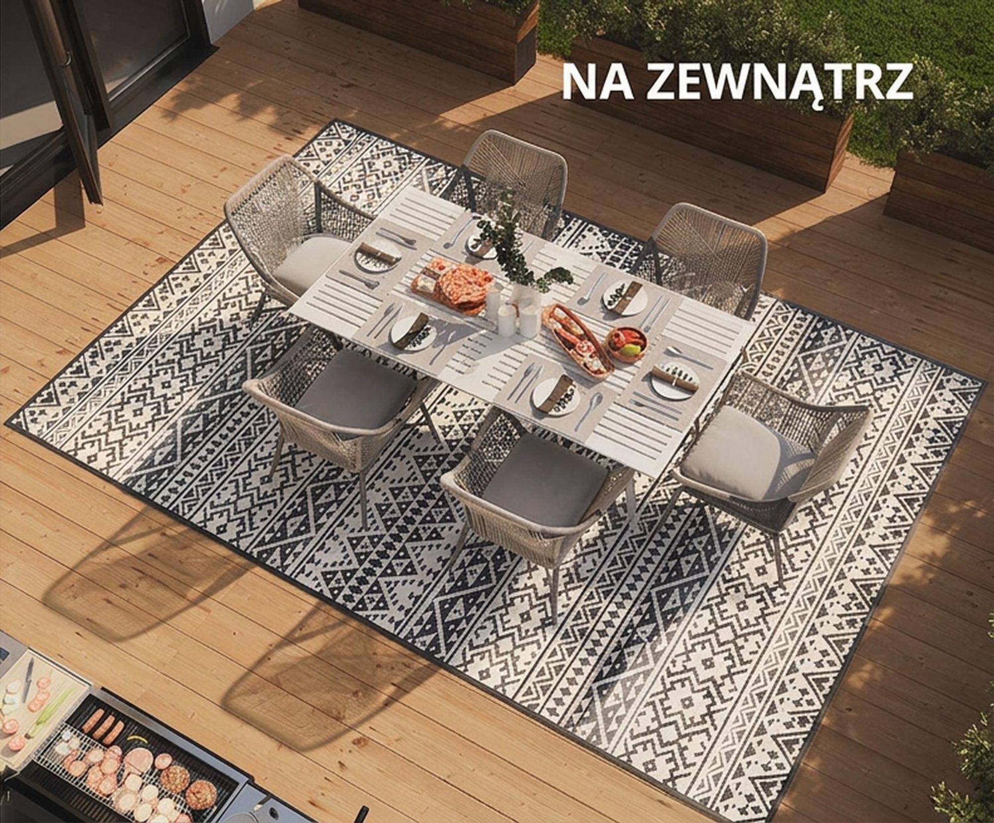 Stół jadalniany na szaro-białym dywanie outdoorowym.