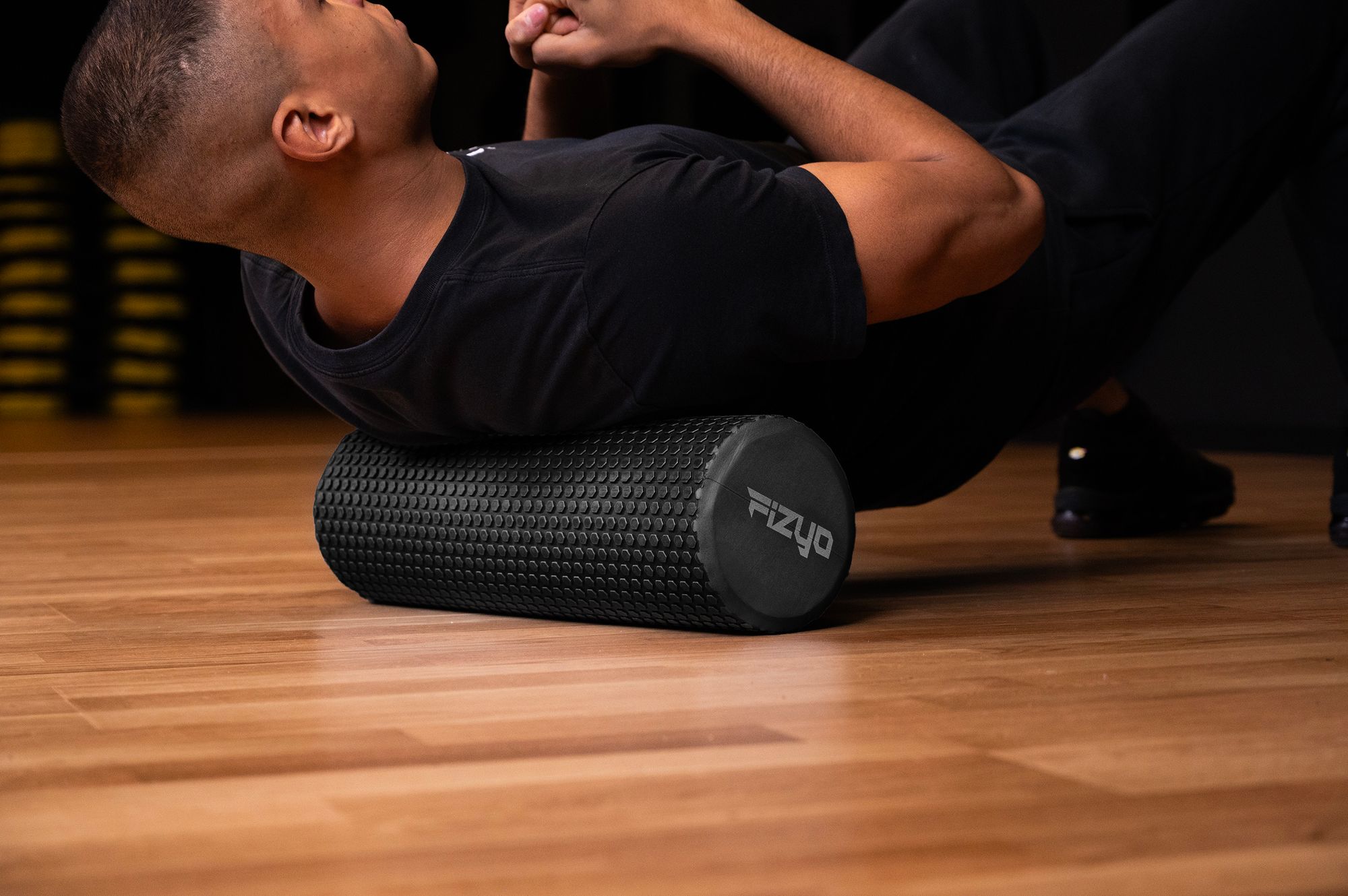 Trening Fitness z wałkiem do masażu z wypustkami 45x15 cm FIZYO — osoba wykonuje ćwiczenia