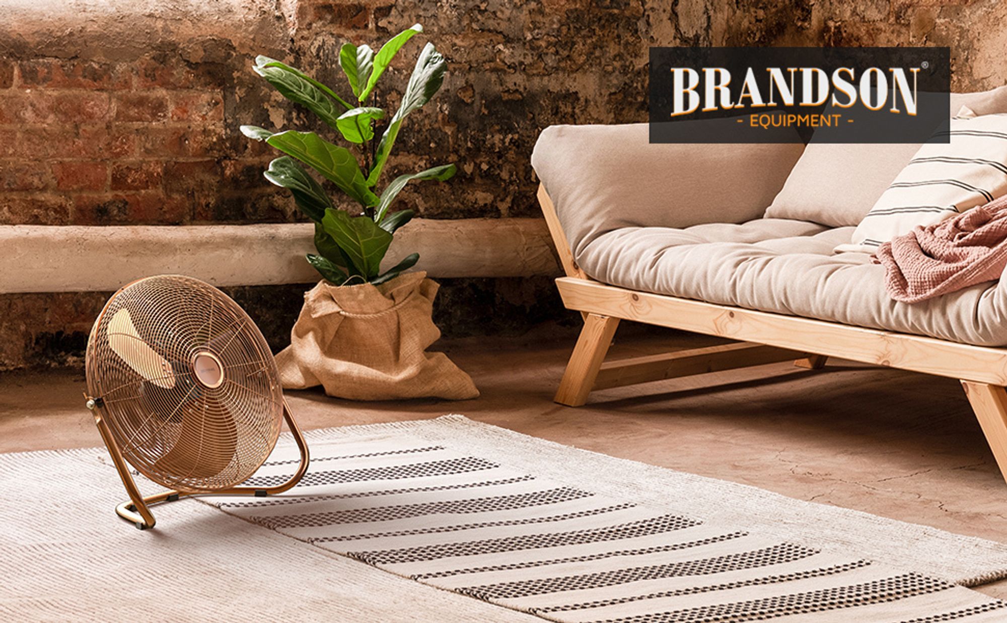 Kupferfarbene Windmaschine auf Teppich neben Holzsofa und Zimmerpflanze im Loft-Stil