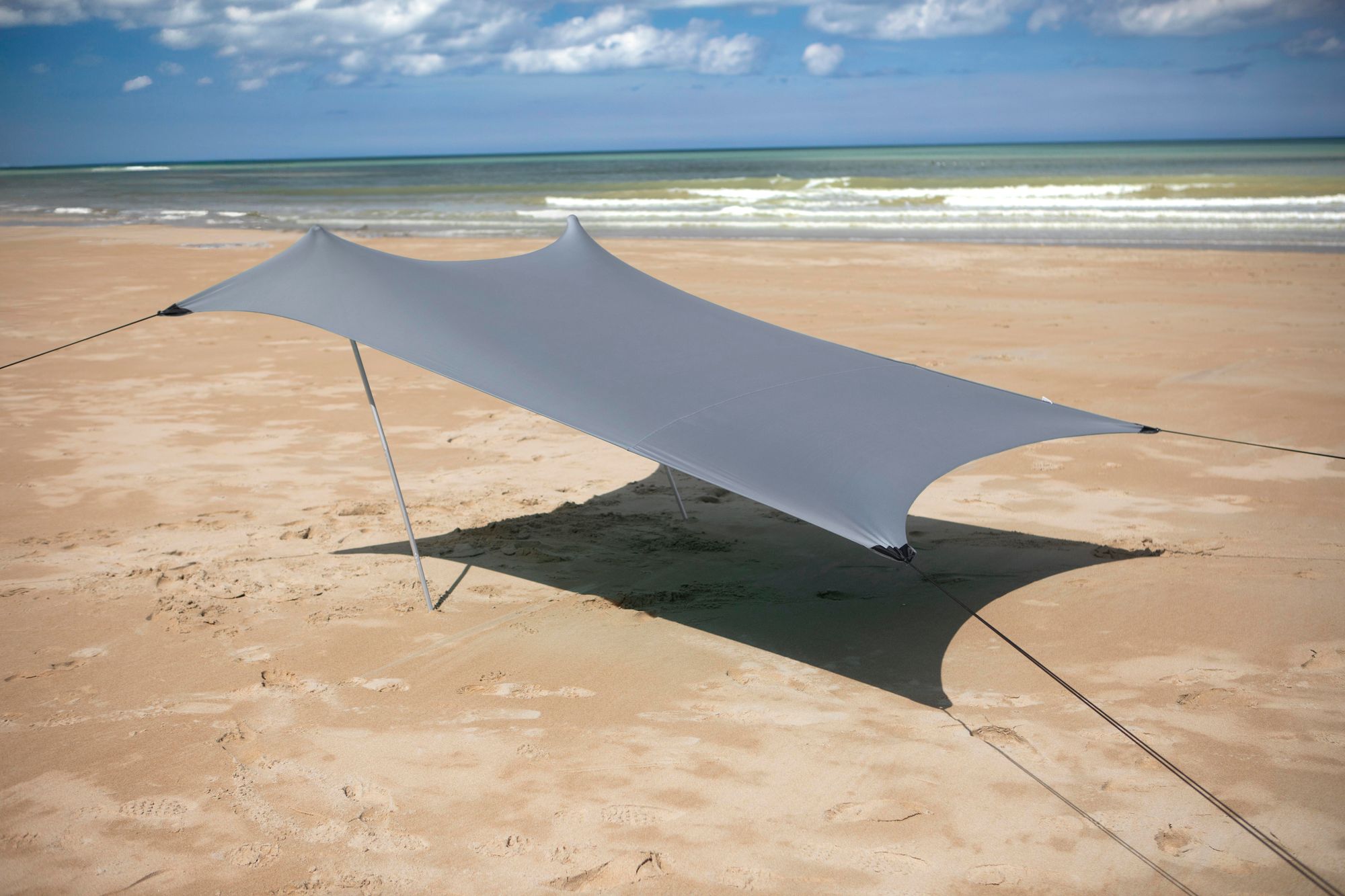 Das Bild zeigt, wie ein Mann das Strandzelt aufstellt